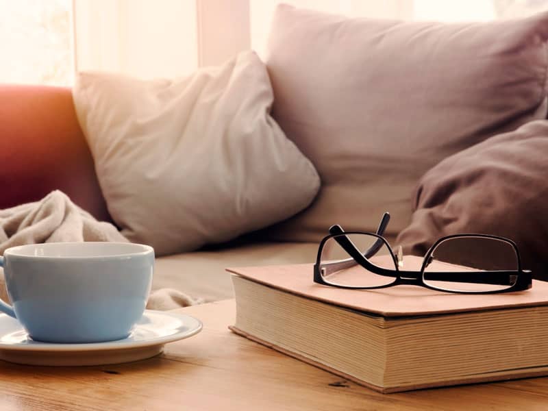 Comfortable looking couch with glasses, book and coffee in the foreground